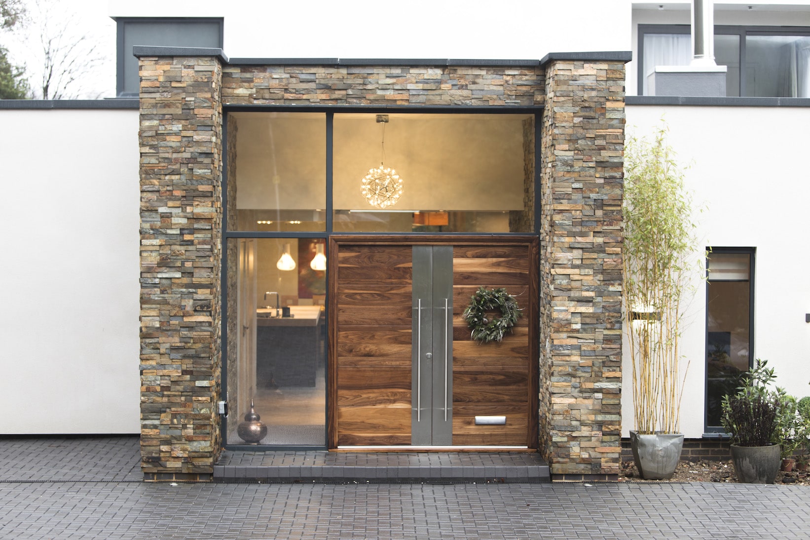 Norstone Slimline Ochre Rock Panels on modern residential entryway with double wooden doors and large glass wall